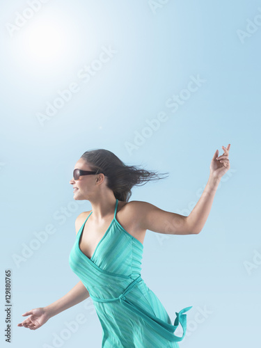 Side view of a young woman with hair blowing towards the wind against the sky