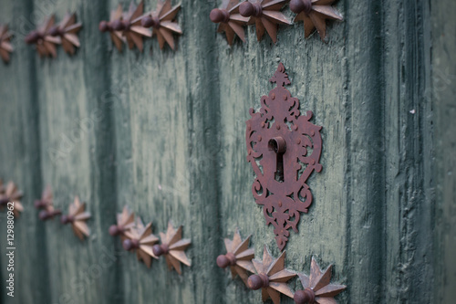 Keyhole in an old paneled wooden door; rusty and weathered