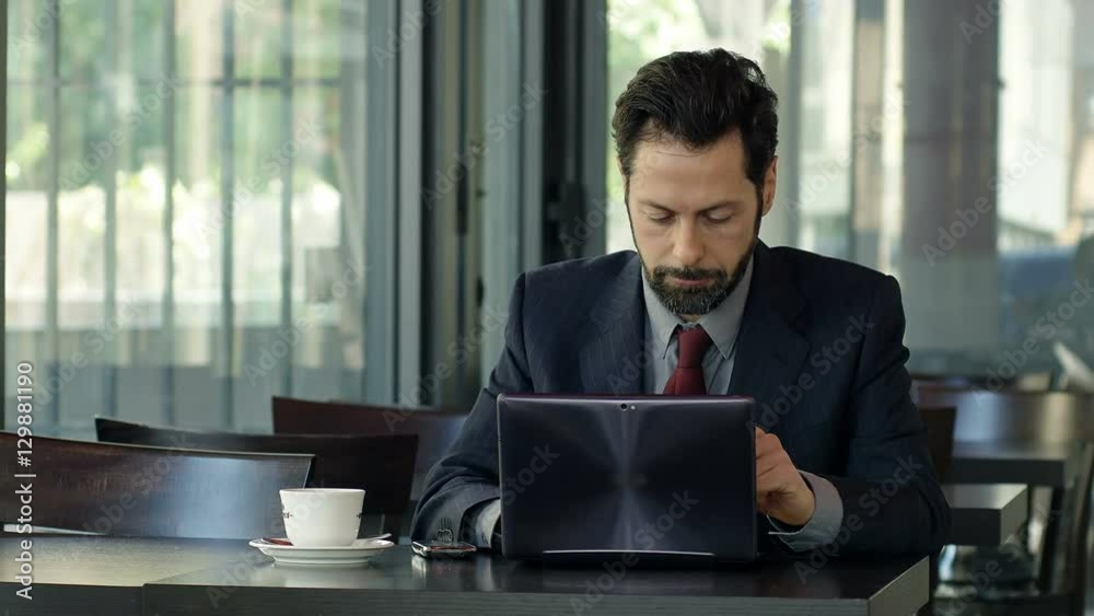angry businessman sitting alone with laptop and mobile phone angry businessman sitting alone with laptop and mobile phone