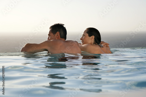 Rear view of happy couple relaxing in infinity pool at resort © moodboard