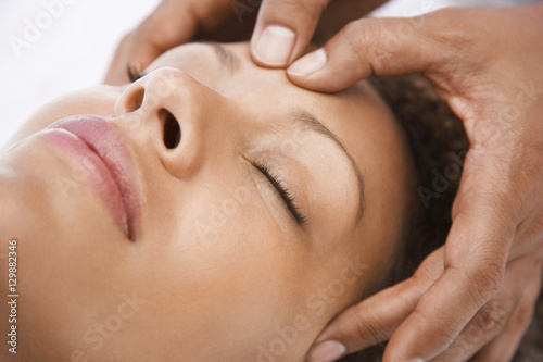 Closeup of young woman receiving head massage from masseur
