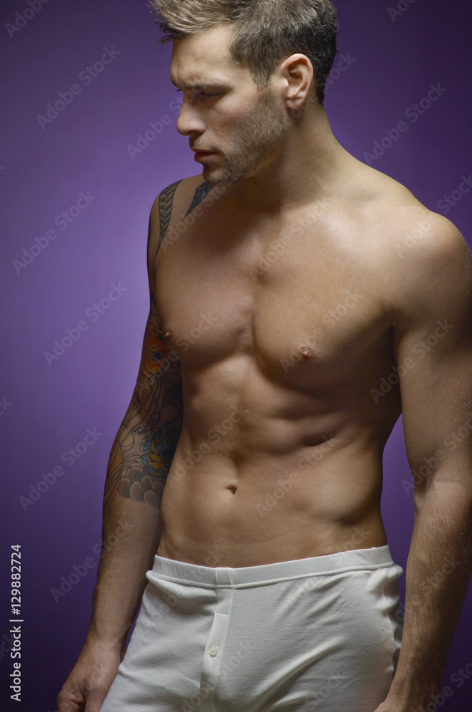 Fototapeta premium Young muscular man isolated over purple background