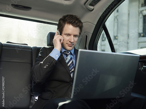 Young businessman using mobile phone and laptop in car © moodboard