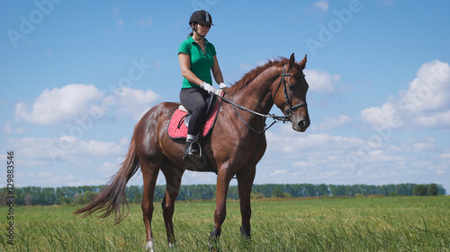 Young woman riding a horse on the green field © kustvideo
