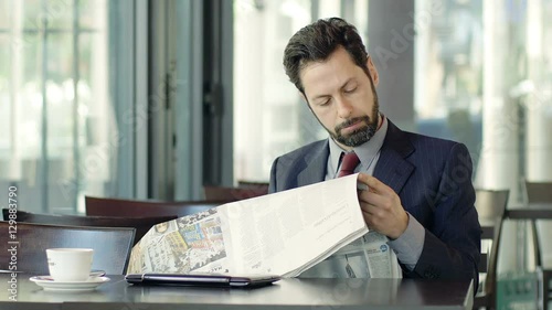 Handsome businee man reading newspaper in a cafe photo