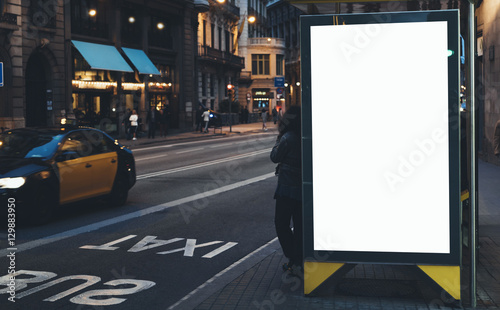 Blank advertising light box on bus stop, mockup of empty ad billboard on night bus station, template banner on background city street in Barcelona, afisha board and headlights of taxi cars photo