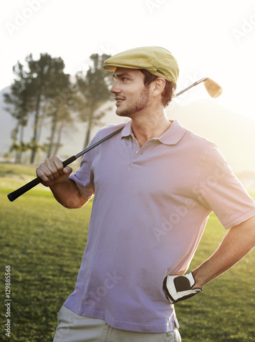 Handsome young male golfer holding club on golf course