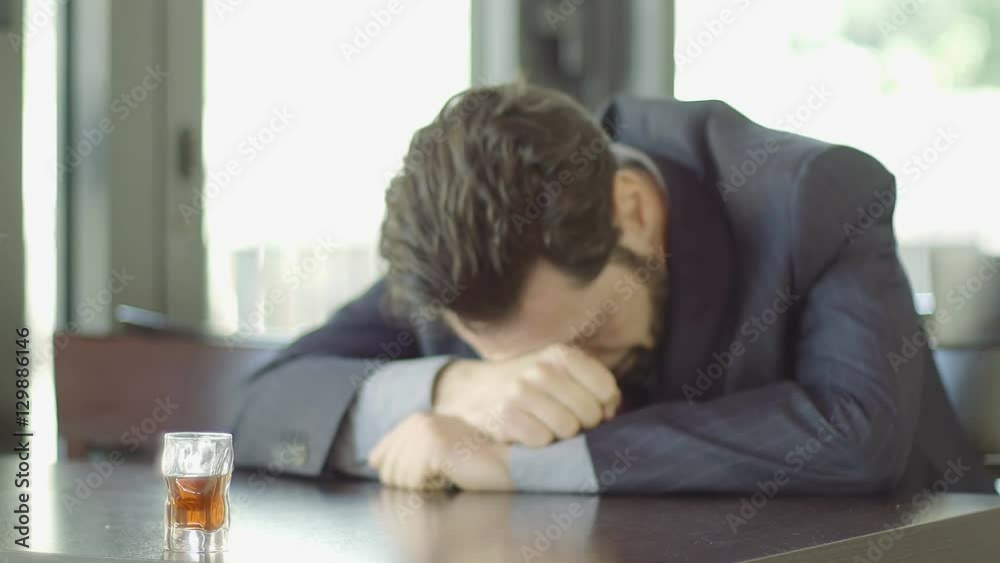 depressed businessman sitting in a cafè with a glass of alcohol depressed businessman sitting in a cafè with a glass of alcohol