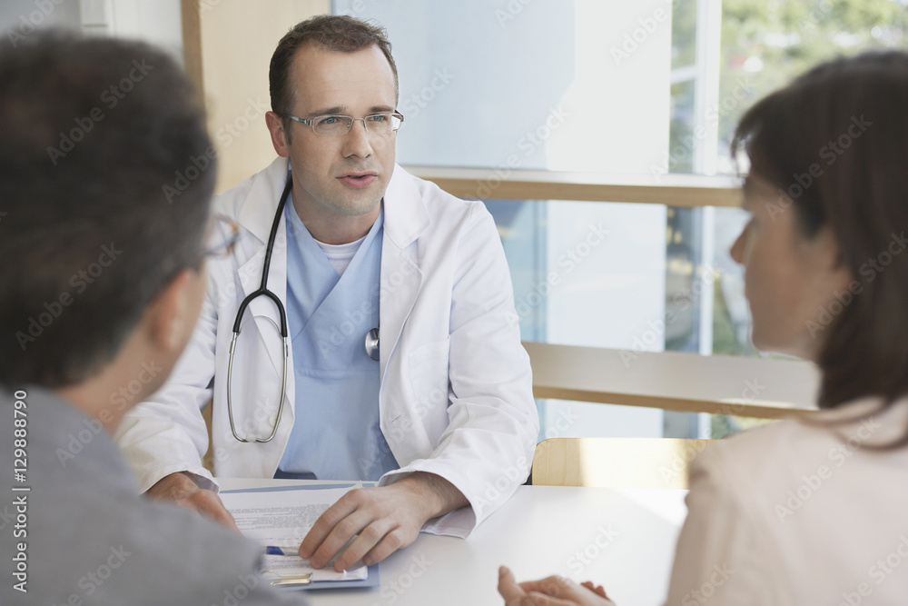 Fototapeta premium Smart doctor conversing with a cropped couple at hospital desk
