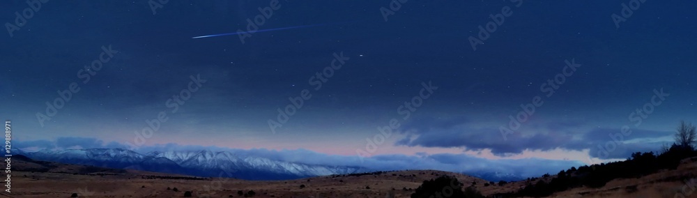 Amazing panoramic night image of shooting star in clear blue sky over the Sierra Nevada mountains