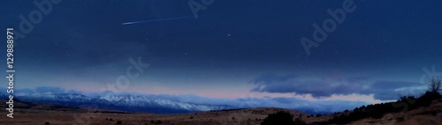 Amazing panoramic night image of shooting star in clear blue sky over the Sierra Nevada mountains © cammie