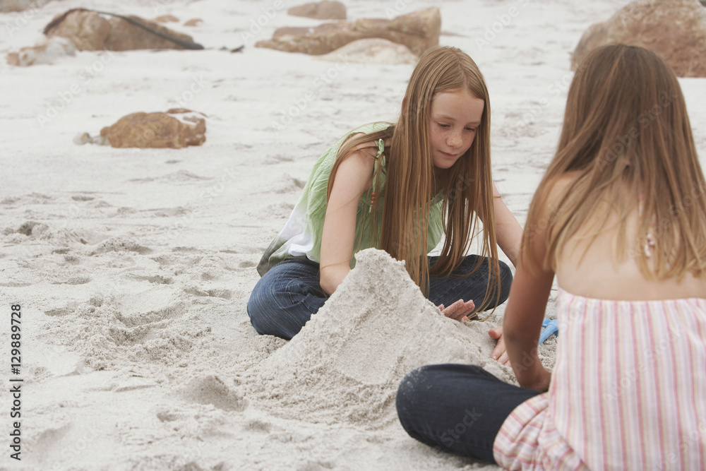 Sisters making sand castle on beach
