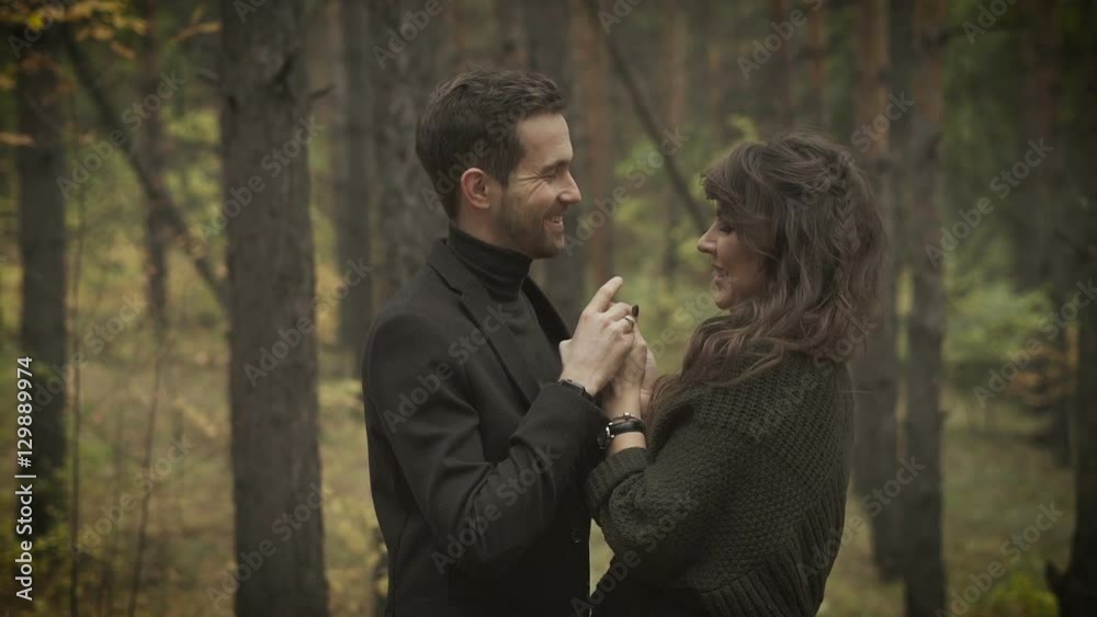 Happy wife and husband spending weekend in the forest. Smiling man and woman standing in the forest with a lot of trees behind, looking at each other and laughing happy. Happy wife and husband spending weekend in the forest. Smiling man and woman standing in the forest with a lot of trees behind, looking at each other and laughing happy.