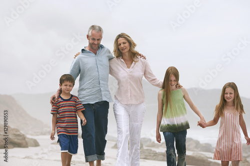 Happy Caucasian couple walking with children at beach