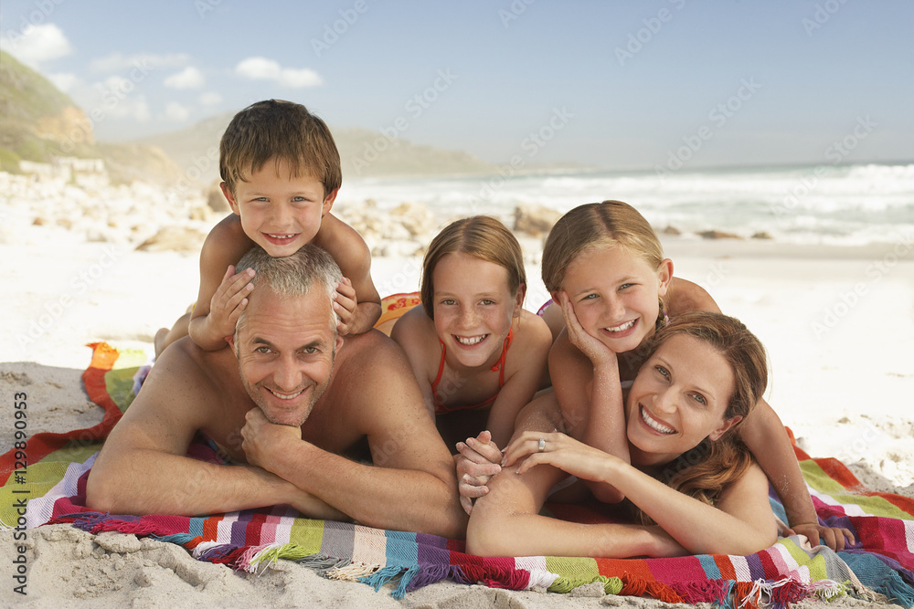 Portrait of happy Caucasian family lying together on blanket at beach Portrait of happy Caucasian family lying together on blanket at beach