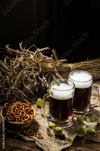 Two tankard beer with wheat and hops , basket of pretzels