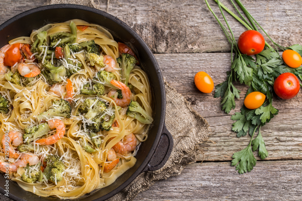 Pasta linguine with shrimps and broccoli in dripping pan on wooden background. Pasta linguine with shrimps and broccoli in dripping pan on wooden background.