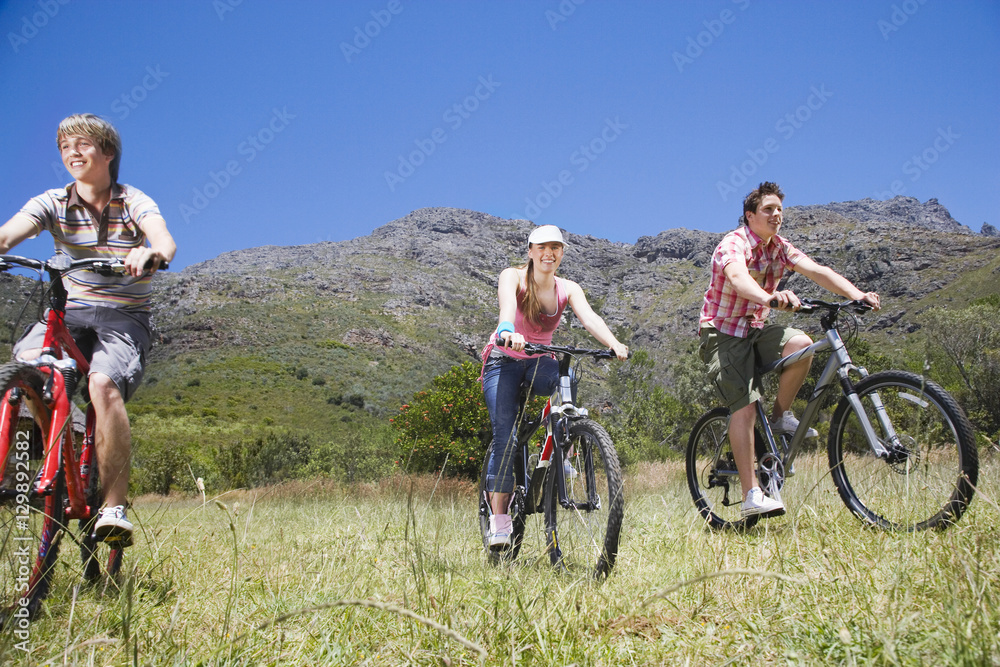 Teenage boys and girl biking with mountain in background