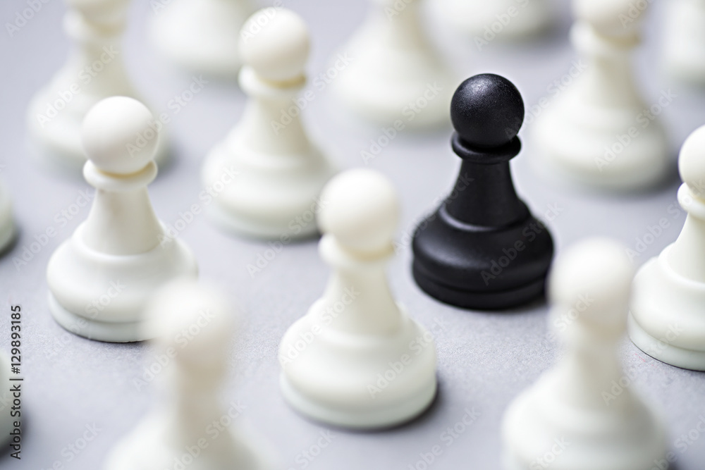 Single black chess piece amongst white ones