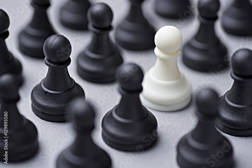 Single white chess pawn amongst black ones