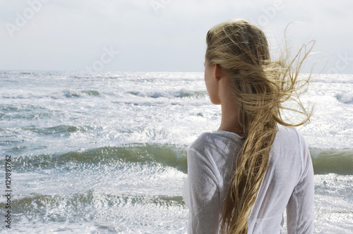 Rear view of a young blond woman looking at the ocean