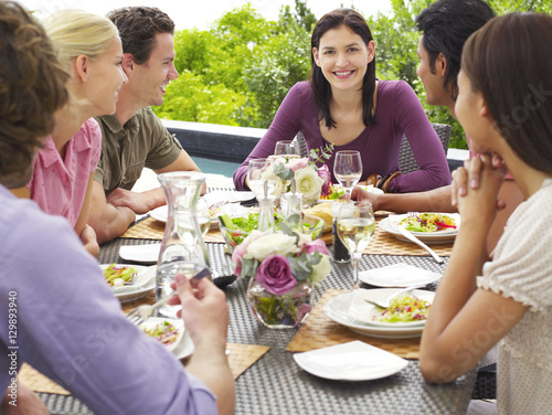 Portrait of happy young woman with multiethnic friends enjoying meal outdoors