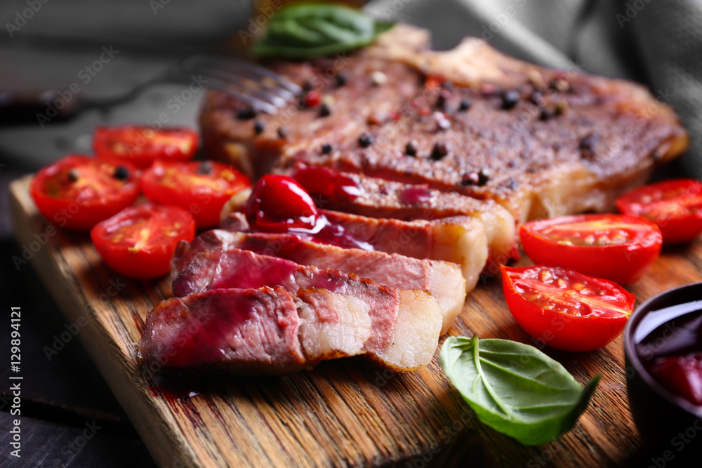 Grilled steak with tomatoes and basil on cutting board, closeup Grilled steak with tomatoes and basil on cutting board, closeup