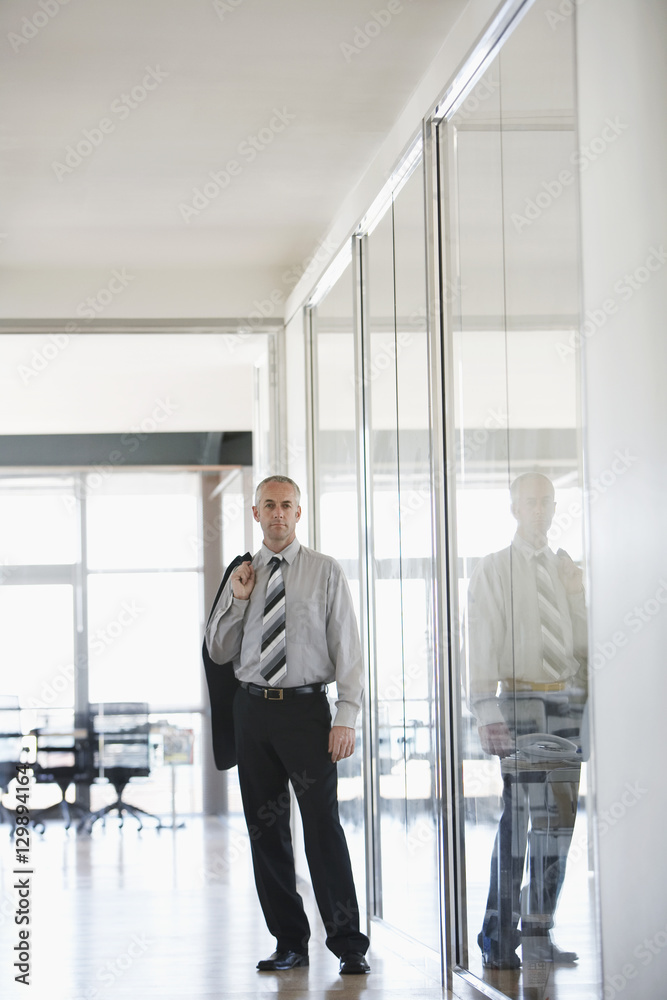 Portrait of confident middle aged businessman standing in office corridor Portrait of confident middle aged businessman standing in office corridor