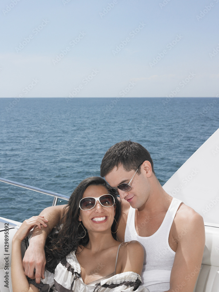 Beautiful young couple wearing sunglasses on yacht at sea