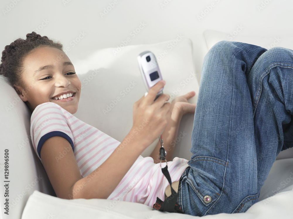 Side view of a cheerful young girl using cellphone Side view of a cheerful young girl using cellphone
