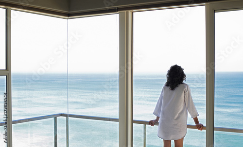 Rear view of young woman looking at sea view from balcony at resort © moodboard