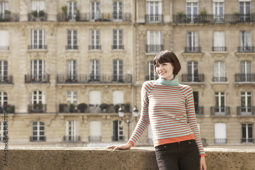 Smiling young woman standing on bridge in front of town houses © moodboard