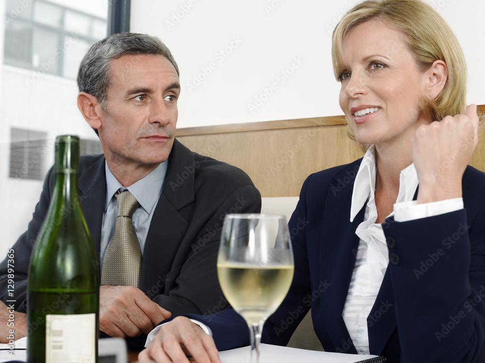 Middle aged business people with wineglass and bottle in restaurant
