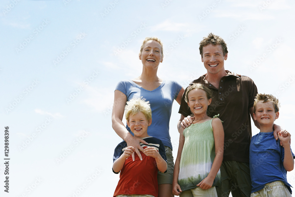 Portrait of happy parents with children standing against sky