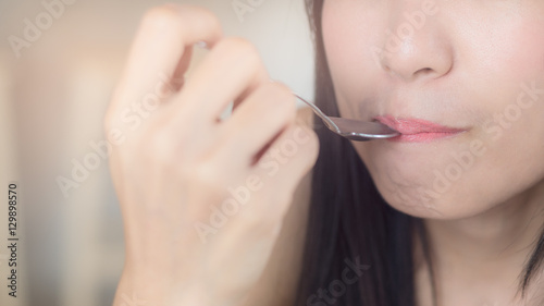 Young Asian woman  lady taste some food or beverage by hold spoon touch lips