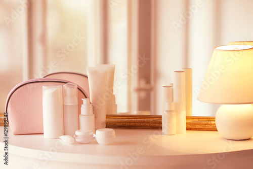 Set of cosmetics and lamp on white table against vintage mirror © Africa Studio