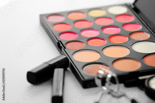 Pallet of eyeshadows and lipstick on white table, close up view