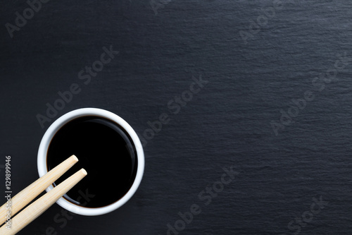 Soy sauce in small white bowl with chopsticks.