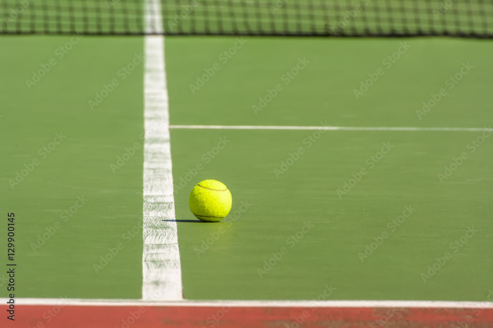 Green tennis balls are in a tennis court.