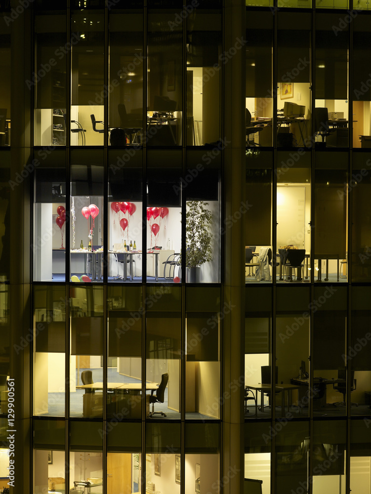 View of empty office decorated with balloons after party through window at night