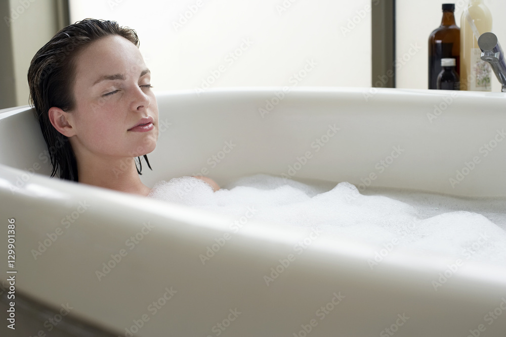 Beautiful young woman relaxing with eyes closed in bathtub Beautiful young woman relaxing with eyes closed in bathtub