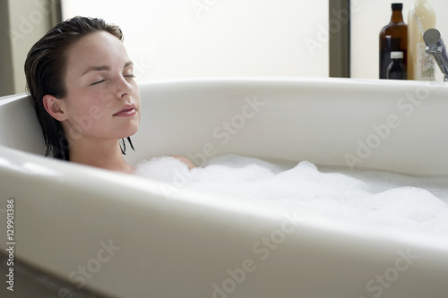 Beautiful young woman relaxing with eyes closed in bathtub