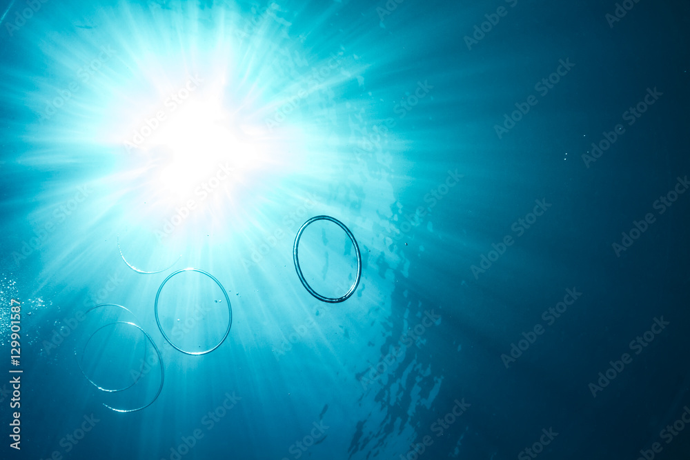 Air bubbles in shape of rings underwater of blue sea in light of sun Air bubbles in shape of rings underwater of blue sea in light of sun
