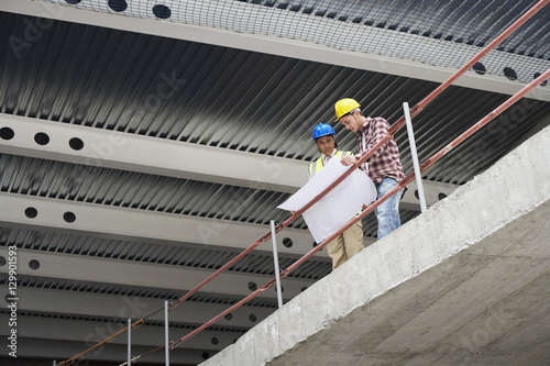 Low angle view of construction manager and worker examining building plans at site