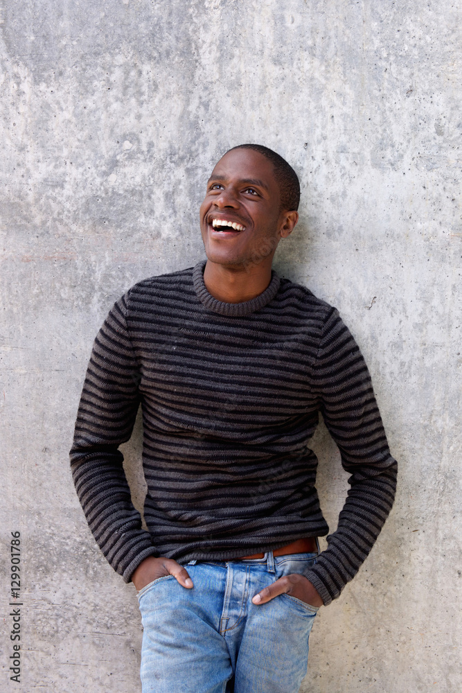 cheerful black guy with hands in pockets looking up