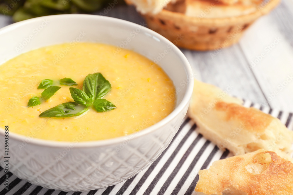 Tasty cornmeal mush with breads and basil leaves on kitchen table, close up view