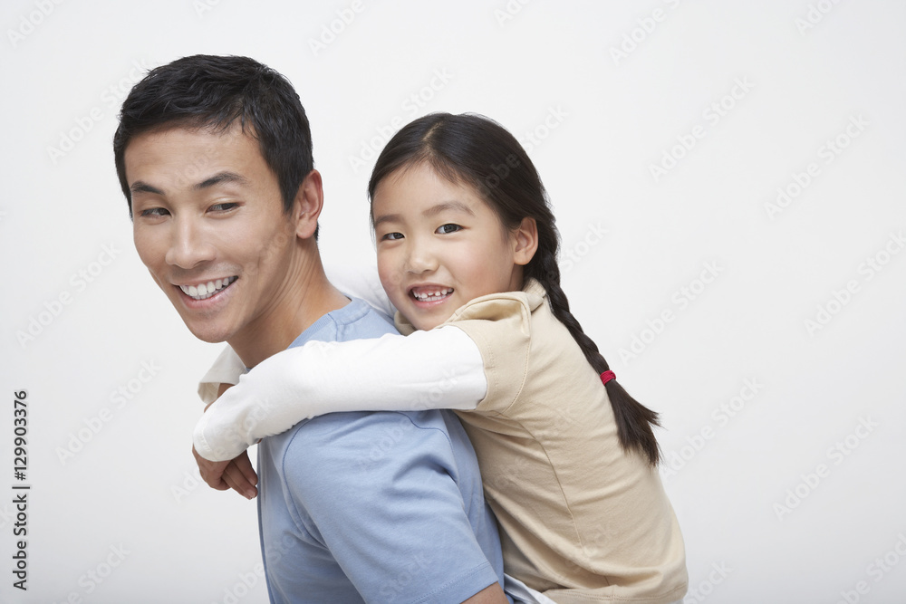 Side view of a young girl getting piggyback ride with father Side view of a young girl getting piggyback ride with father