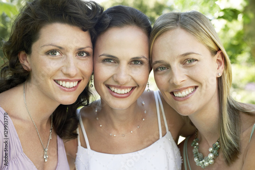 Closeup portrait of three female friends smiling together outdoors