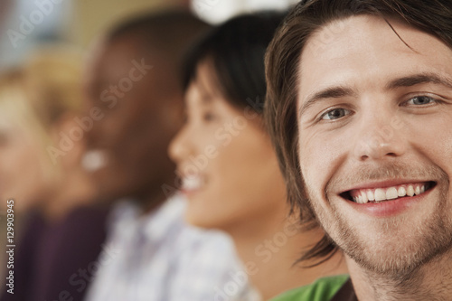 Portrait of happy young businessman with colleagues in background