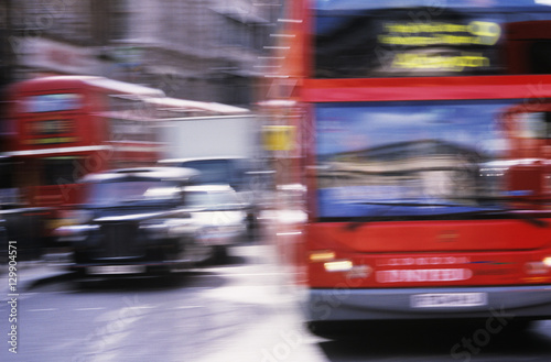 Red buses and black cabs on road in London motion blur